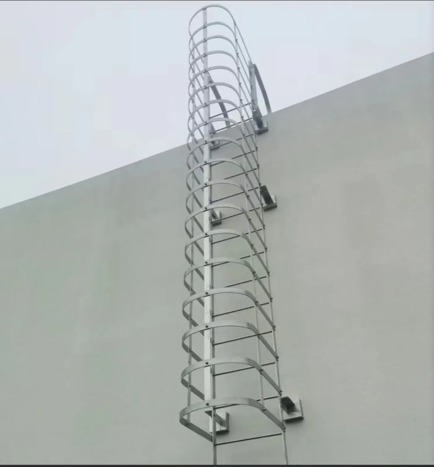 Escada fixa vertical com gaiola de proteção de aros azuis, fabricada em aço